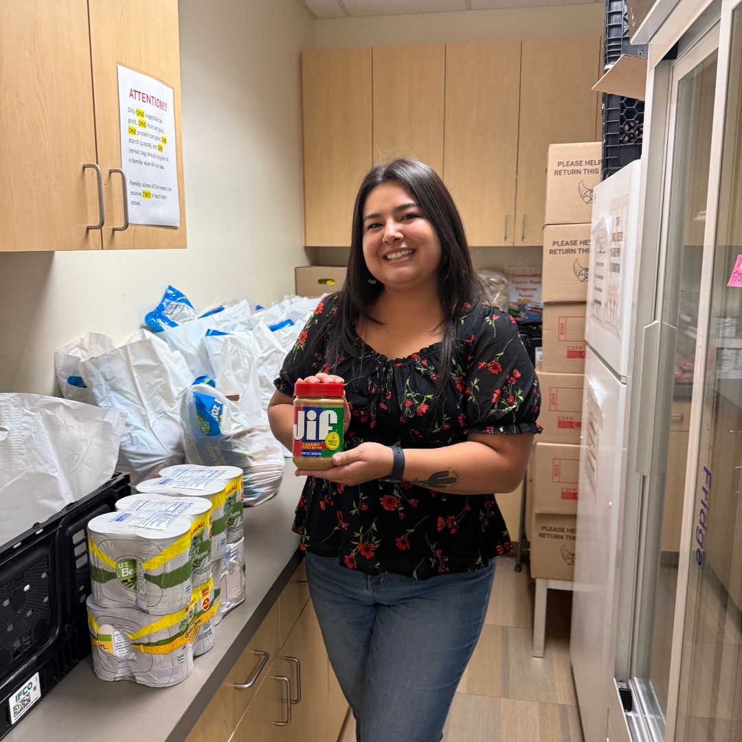 A NATIVE HEALTH team member with donated food and pantry supplies